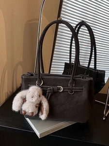 Deep brown leather tote bag with white contrast stitching and plush rabbit charm