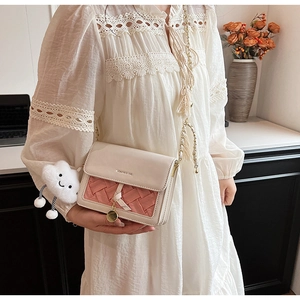 Detail of white leather crossbody bag with pink woven texture and cloud charm
