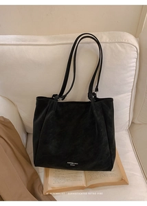 Close-up of black matte suede tote bag with brand logo on a minimalist home background