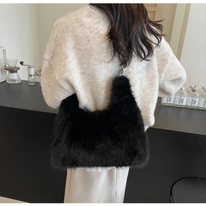 Close-up of black plush faux fur shoulder bag with silver hardware on model