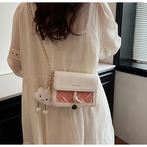 Close-up of pink woven crossbody bag with gold chain and cute white cloud pendant