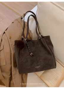 Detailed view of brown leather tote bag with furry charm and vintage brand logo