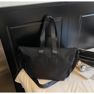 Detail of black large-capacity tote bag with adjustable shoulder strap and water-repellent nylon
