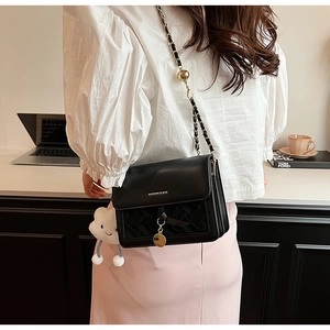 Detail of black crossbody bag with woven flap, chain strap and gold adjustment ball