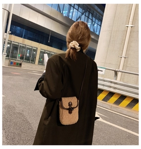 Outdoor shot of a warm brown faux shearling crossbody bag with leather trim and horn button