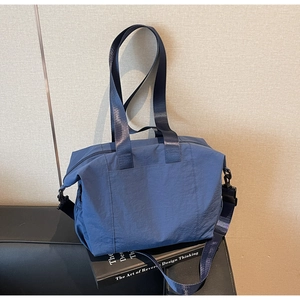 Detail of navy blue nylon tote bag showing durable side buckles and adjustable shoulder strap