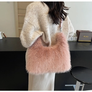 Pink faux fur crossbody bag with leather strap worn over a beige knit sweater