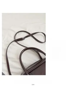 Detail shot of dark brown glossy leather handbag with silver metal buckle and adjustable strap