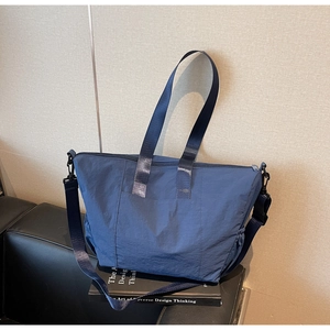Detail of dark blue tote bag showing waterproof nylon texture and side drawstring pocket