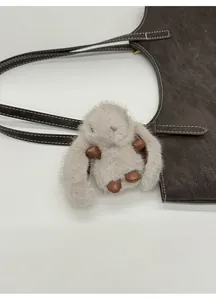 Close-up of a fluffy grey bunny bag charm attached to a brown vintage tote bag handle