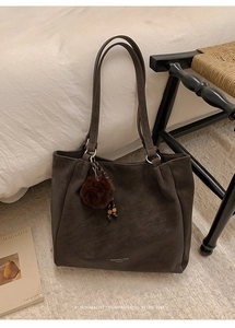 Detail showing the matte texture and plush ball charm on a vintage dark brown tote bag