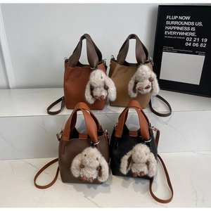 Detail of four colorful lychee pattern leather bucket bags with rabbit plush pendants