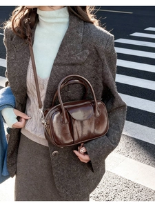 Detail of dark brown oil wax leather bowling bag with glossy finish and top handles