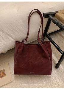 Detailed macro of textured burgundy leather tote bag with silver ring shoulder straps