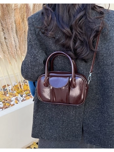 Macro detail of the dark reddish-brown glossy patent leather and embossed logo on the bag