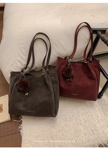Detail of minimalist tote bags in dark brown and burgundy with plush ball charms