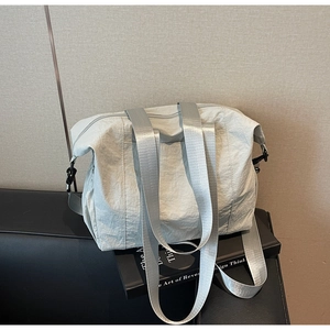 Detail of light grey nylon tote bag with pleated texture and wide fabric shoulder strap