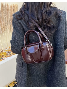 Detail of dark red oil wax leather handbag with glossy texture and shoulder strap