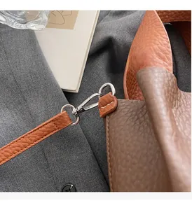 Close-up of contrast litchi grain leather bucket bag with silver hardware and stitching