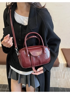 Detail of burgundy glossy leather bowling bag with brand logo and adjustable strap