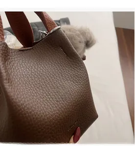 Close-up of brown litchi pattern leather bucket bag with white contrast stitching details