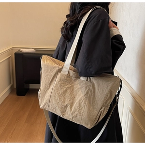 Detail view of khaki pleated tote bag showing the unique wrinkled texture and strap hook