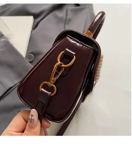 Macro shot of gold metal hook and pearl handle on vintage red patent leather bag