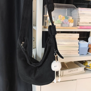 Détail du sac hobo en suède noir avec bandoulière à nœud et breloque monstre en peluche