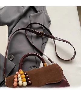 Detail view of retro brown suede handbag with decorative wooden beads and gold hardware