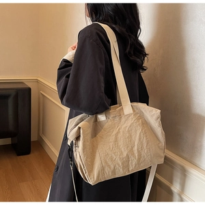Detail view of a large beige nylon tote bag worn by a model for daily commuting style