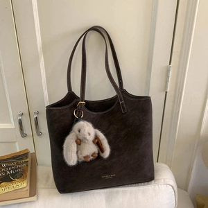 Detail of dark brown suede tote bag with contrast stitching and rabbit plush charm