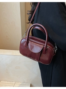 Detail of dark red oil wax leather bowling bag with high gloss finish and silver hardware