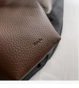 Close-up of deep brown pebbled leather texture with a high-quality embossed logo