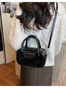 Detail of glossy black bowling bag worn as a shoulder bag with adjustable strap