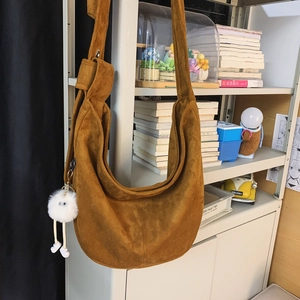 Détail d'un grand sac croissant en daim marron avec un joli porte-clés monstre blanc