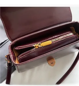 Close-up of a smooth golden zipper and internal pocket in a burgundy leather handbag