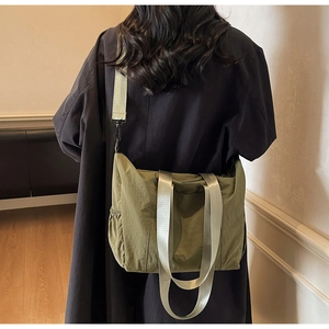 Detailed back view of an olive green nylon tote bag worn with a dark trench coat