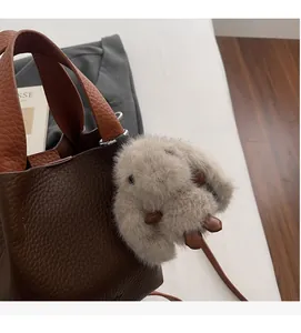 Close-up of brown litchi leather bucket bag featuring a cute plush bunny charm detail
