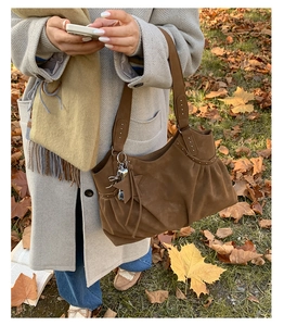 Detail of dark brown suede tote bag with silver studs and star shaped leather charm