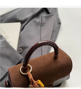 Detail of vintage brown suede handbag featuring round handles and colorful beaded charm