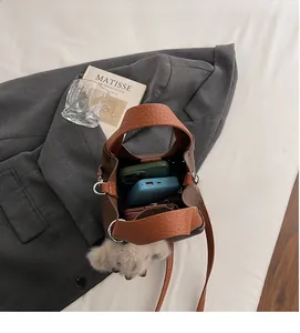 Macro shot of brown pebble leather bucket bag interior holding two phones and a wallet