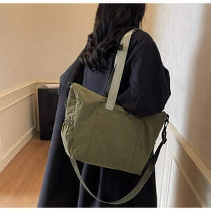 Detail of army green nylon tote bag with drawstring and wide strap worn by a model