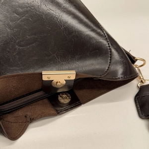 Detail shot of the vintage brown crossbody bag showing magnetic buckle and gold zipper closure