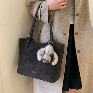 Dark gray matte leather tote bag with a cute plush rabbit charm shown on a model