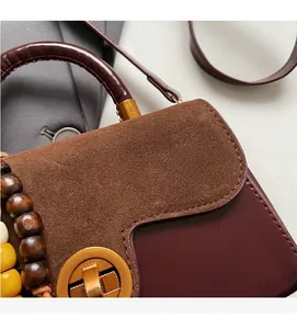 Detail of vintage tote bag featuring brown suede stitching and a metal twist lock