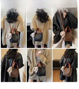 Close-up of pebble leather bucket bag in black and caramel with plush rabbit charm