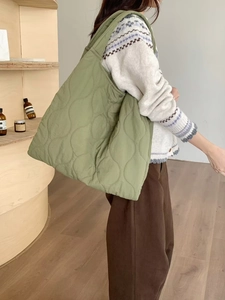 Detail of green quilted nylon tote bag showing spacious capacity and shoulder strap