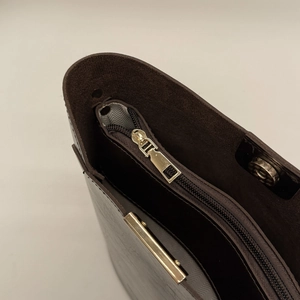 Detail of dark brown leather handbag showing zipper closure and herringbone fabric lining