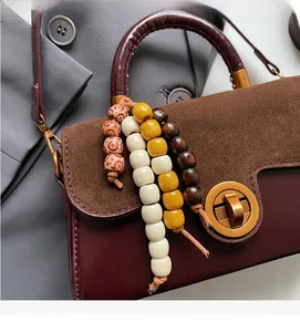 Detail of red leather and brown suede crossbody bag with vintage wooden beads tassel