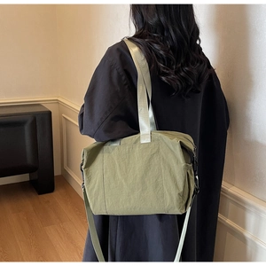 Close-up of olive green nylon tote bag with wide strap and large front pocket detail